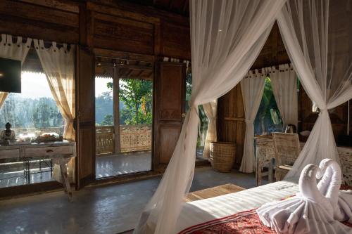 a bedroom with a bed and a desk and windows at Umah Capung Sebatu Villas in Tegalalang