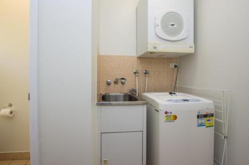 uma pequena cozinha com um lavatório e um frigorífico em SAILS 9 Beachfront Getaway Horseshoe Bay em Horseshoe Bay
