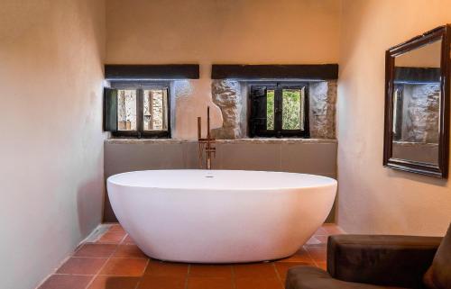 a large white tub in a bathroom with two windows at Castello Di Tornano Wine Relais in Gaiole in Chianti