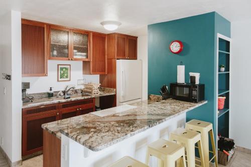 a kitchen with a counter and a blue wall at Holualoa Garden 103 in Kailua-Kona