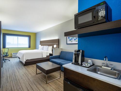 ein Hotelzimmer mit einem Bett und einer Küche mit einem Waschbecken in der Unterkunft Holiday Inn Express Hotel & Suites Beaumont Northwest, an IHG Hotel in Beaumont
