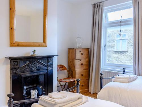 a bedroom with a fireplace and a bed and a mirror at Anchor Cottage in Whitstable