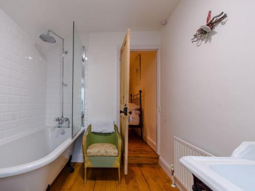 uma casa de banho com uma banheira e uma cadeira verde. em Anchor Cottage em Whitstable