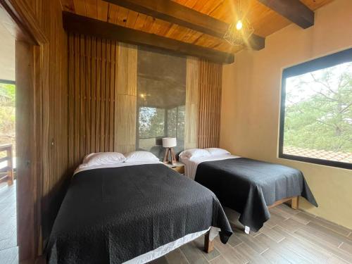 a bedroom with two beds and a window at Cabaña de la Cascada in Mazamitla