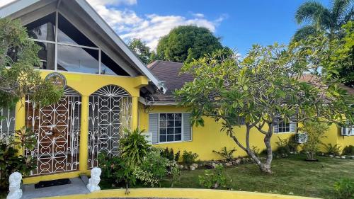 a yellow house with a gate in a yard at Yancey Largo Villa with Private Pool in Montego Bay