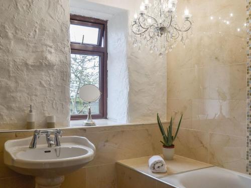 a bathroom with a sink and a tub and a chandelier at The Calving Shed in Neilston