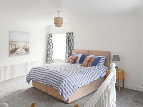 a white bedroom with a bed and a window at Old Manse Annex in Town Yetholm