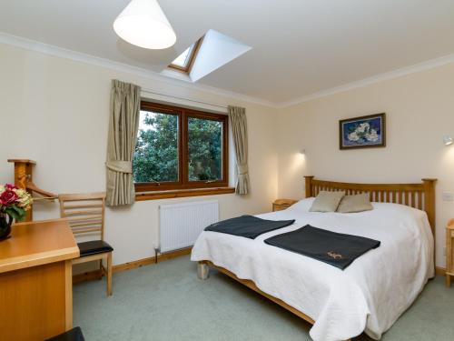 a bedroom with a bed and a desk and a window at Seabird Cottage in Broadford