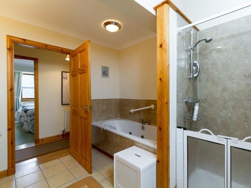 a bathroom with a tub and a glass shower stall at Seabird Cottage in Broadford