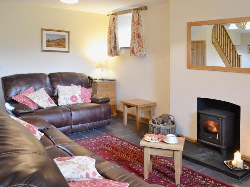 a living room with a leather couch and a fireplace at Llechwedd Mawr in Talybont