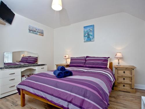 a bedroom with a purple bed with a blue stuffed animal on it at Applebee Cottage in Bridport