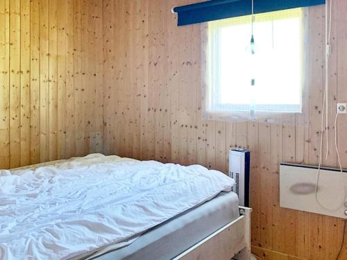 een bed in een houten kamer met een raam bij Holiday home HÖKERUM II in Hökerum