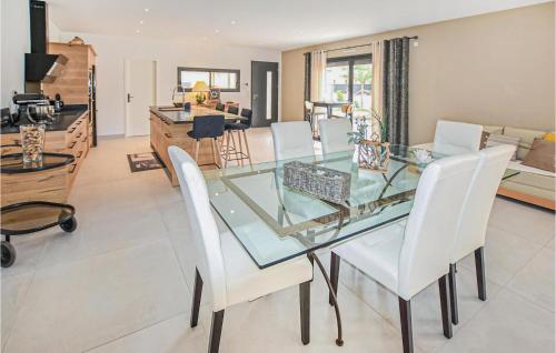une salle à manger avec une table en verre et des chaises blanches dans l'établissement Amazing Home In Robion, à Robion