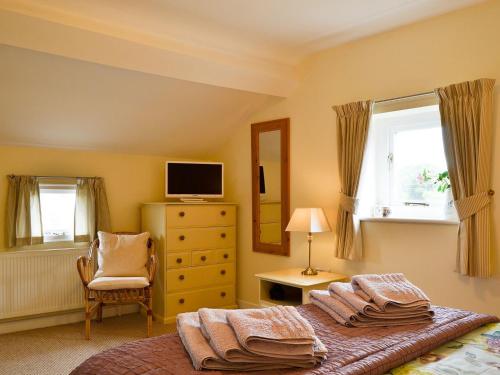 a bedroom with a bed and a television and a chair at Broadoak Barn in Ellesmere