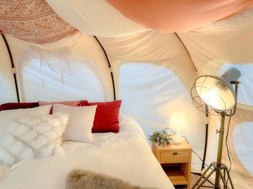 a bedroom with a bed with red and white pillows at ファームグランピング　ル・クロ　かいづか　いぶきヴィレッジ in Kaizuka