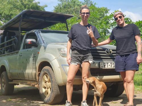 two people standing in front of a truck with a dog at Ceylon Resort in Wilpattu