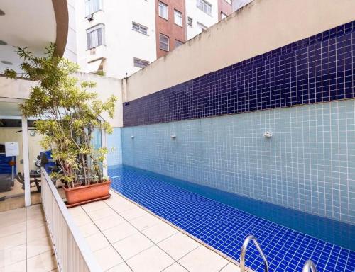 una piscina con azulejos azules en un edificio en Flat com serviço completo e vista Cristo, en Río de Janeiro