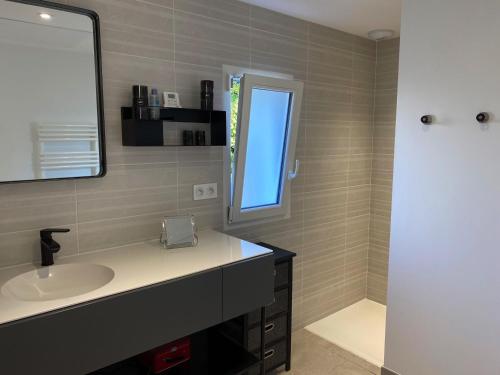 une salle de bain avec un lavabo, un miroir et une fenêtre dans l'établissement Maison à Jard-sur-Mer, 500m de la Plage, 2 Chambres, Climatisation, Parking et Jardin Clôturé - FR-1-336-124, à Jard-sur-Mer