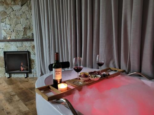 a bottle of wine and two glasses on a bath tub at Monte Mauá Chalés in Visconde De Maua