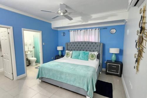 a blue bedroom with a bed and a ceiling fan at Snooze at Oceanpointe in Lucea