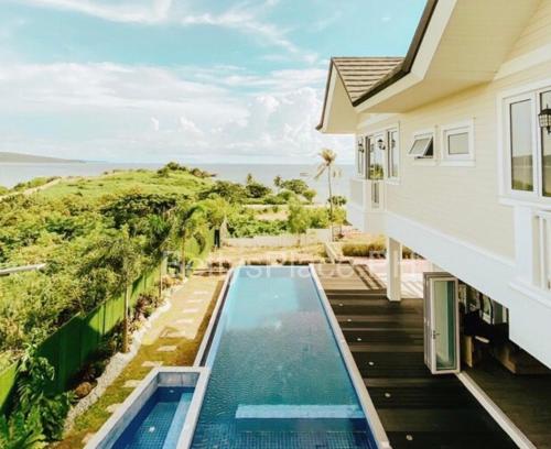 a house with a swimming pool next to the ocean at 4 Bedroom Beachfront House with Private Pool in Batangas in Nasugbu