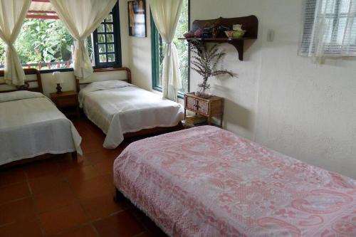 1 dormitorio con 2 camas y ventana en Alejandría, reserva natural y las 7 cascadas, en La Vega