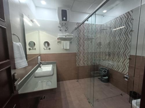 a bathroom with a glass shower and a sink at The Nature Trinket Regency in Dalhousie