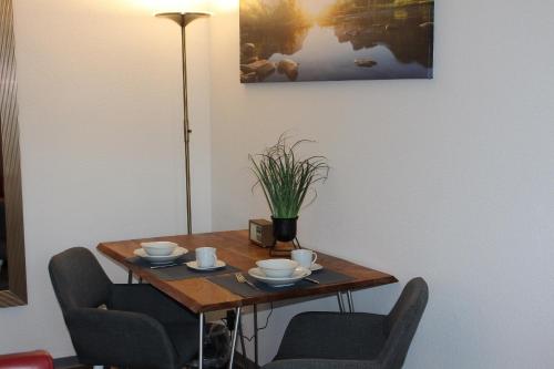 einen Tisch mit 2 Stühlen und einen Tisch mit Tassen und Untertassen in der Unterkunft Haus am See HS 470 B in Hahnenklee-Bockswiese