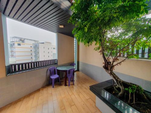 a balcony with a table and purple chairs and a tree at LEHA Saigon Hotel Airport in Ho Chi Minh City