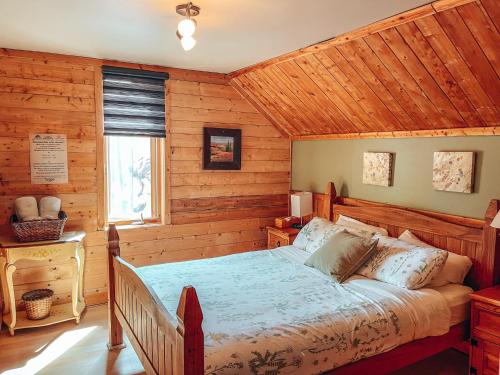 een slaapkamer met een bed in een blokhut bij Gîte B&B du Village in Saint Mathieu Du Parc