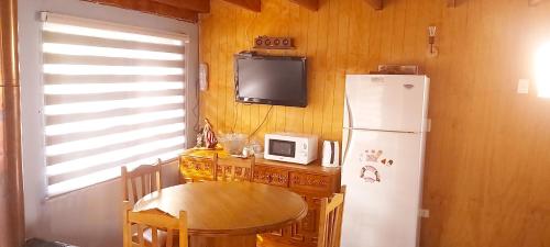 cocina con mesa y nevera blanca en Cabaña Pellines, en Coñaripe