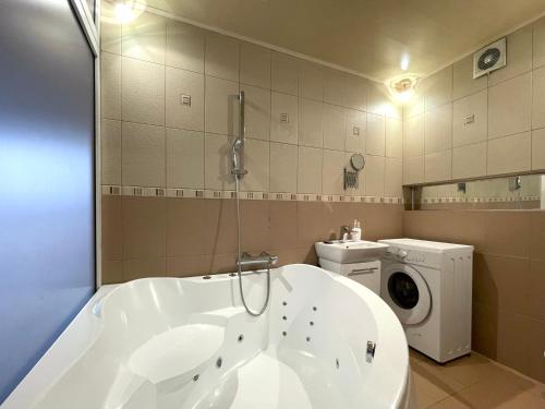 y baño con bañera y lavadora. en 2-х комн квартира с двухместным джакузи, en Petropavlovsk