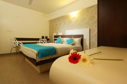 a bedroom with a bed and a flower on a table at moriz inn in Mysore