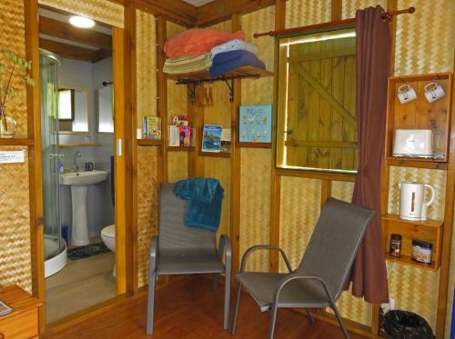 uma casa de banho com uma mesa, 2 cadeiras e um lavatório. em la Cabane de la Vallee em Dumbéa
