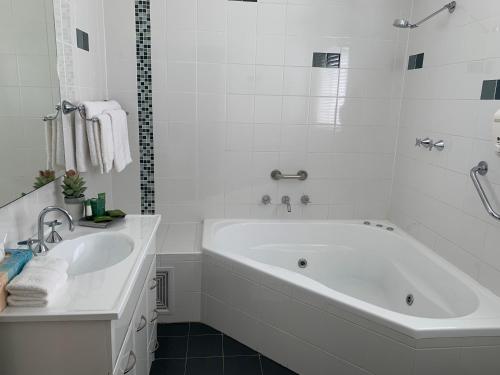 a white bathroom with a tub and a sink at Pelicans Rest Shellharbour in Shellharbour