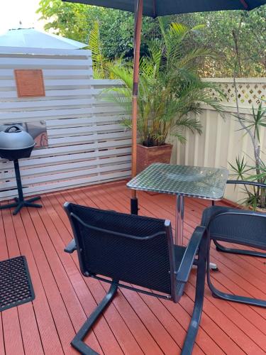 a patio with a table and a chair and an umbrella at Pelicans Rest Shellharbour in Shellharbour