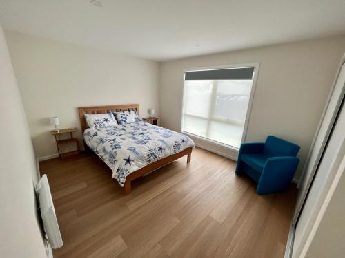 1 dormitorio con 1 cama y 1 silla azul en Shell Cottage en Coles Bay