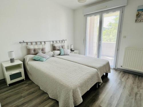 a white bedroom with two beds and a window at Appartement Cambo-les-Bains, 2 pièces, 2 personnes - FR-1-495-14 in Cambo-les-Bains