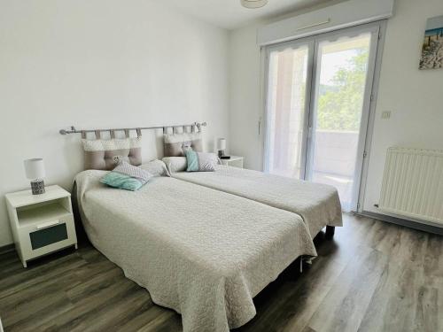 una camera da letto bianca con due letti e una finestra di T2 à Cambo-Les-Bains, balcon, parking privé, près des thermes - FR-1-495-14 a Cambo-les-Bains