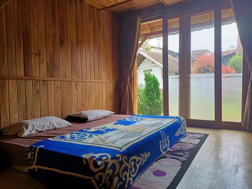 a bedroom with a bed and a large window at ADK Papandayan Homestay & Tour in Tjisurupan