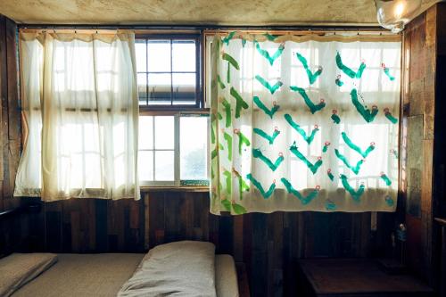 a bedroom with a window with birds on the curtains at Guest House CARAPAN in Kagoshima