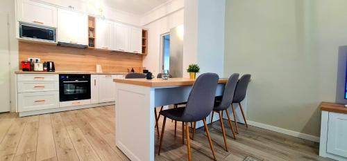 a kitchen with white cabinets and a blue island with chairs at Apartament momA Oradea in Oradea
