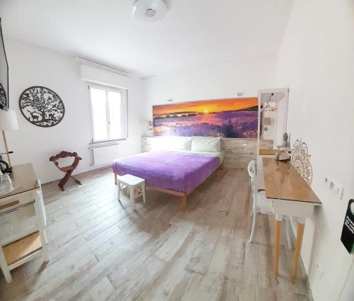 - une chambre avec un lit violet et un bureau dans l'établissement BioBenessere Eco-B&B -Adults Only- Moto&Bike Parking, à Arezzo