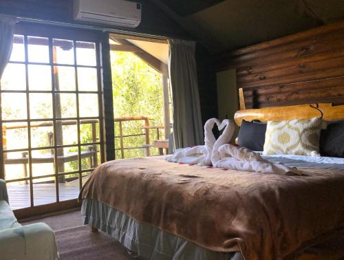 dos cisnes están sentados en una cama en un dormitorio en Teniqua Treetops, en Sedgefield