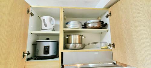 a cupboard filled with pots and pans at Tagaytay Nordic Nest Staycation at Wind Residences with Netflix Wifi near Sky Ranch in Tagaytay