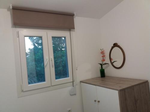 Dieses weiße Zimmer verfügt über ein Fenster und einen Spiegel. in der Unterkunft Seaside house for 8 close to Olympia & the beach in Levendokhórion