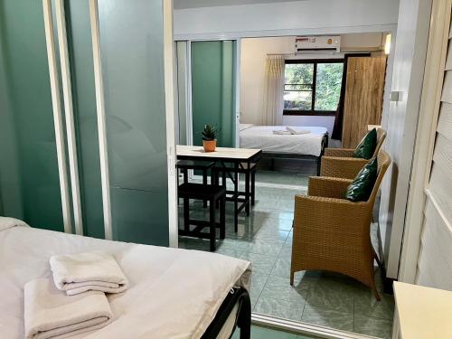 a small room with a bed and a table and chairs at Pakdee House in Udon Thani