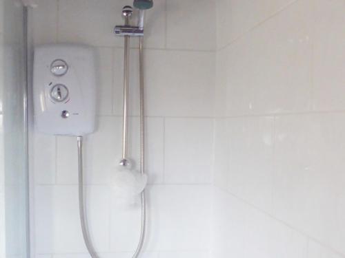 a shower in a white tiled bathroom with a shower at Southview in Porchfield