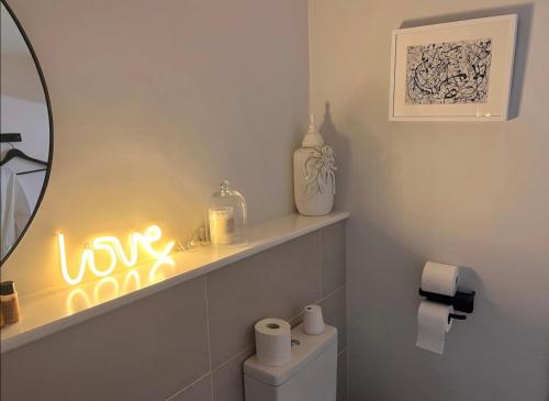 a bathroom with a toilet with a neon sign on the wall at Three Acorns Court in Sandwich