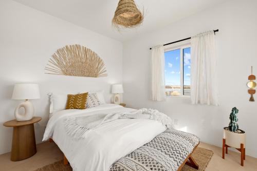 a white bedroom with a bed and a window at Hot Tub, Yoga Room, Cowboy Pool, Firepit in Joshua Tree